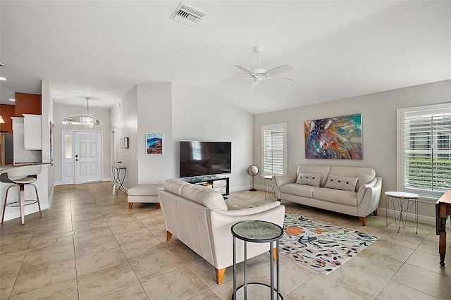 tiled living room featuring plenty of natural light, lofted ceiling, and ceiling fan with notable chandelier