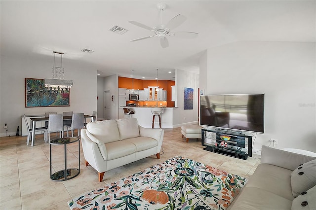 living room with ceiling fan with notable chandelier, lofted ceiling, and light tile patterned flooring