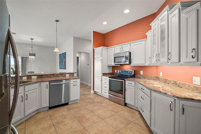 kitchen with white cabinetry, light stone counters, pendant lighting, light tile patterned floors, and appliances with stainless steel finishes