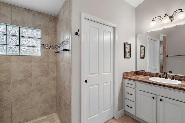 bathroom featuring tiled shower, vanity, and tile patterned flooring