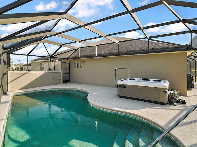 view of pool featuring glass enclosure, a patio area, and a hot tub