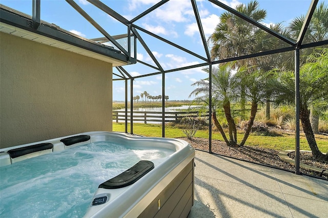 view of patio / terrace with a lanai, a water view, and a hot tub