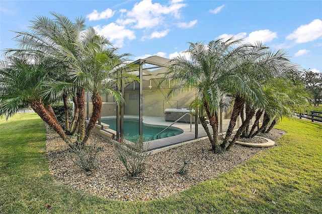 view of swimming pool with a lanai and a lawn