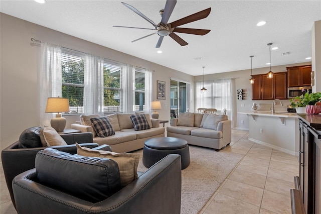 tiled living room with ceiling fan, sink, and a textured ceiling