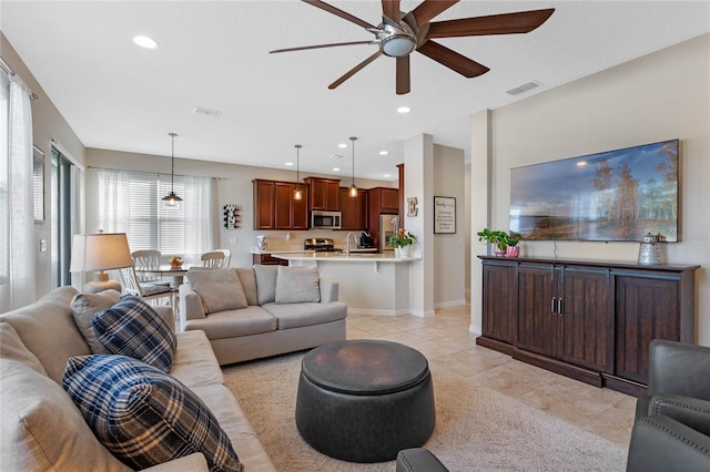 tiled living room featuring ceiling fan and sink