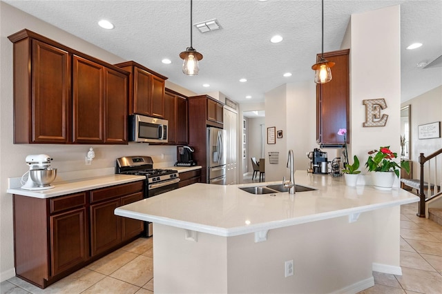 kitchen featuring kitchen peninsula, appliances with stainless steel finishes, a textured ceiling, sink, and hanging light fixtures