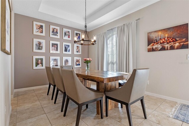 dining space featuring a chandelier, light tile patterned floors, and a tray ceiling