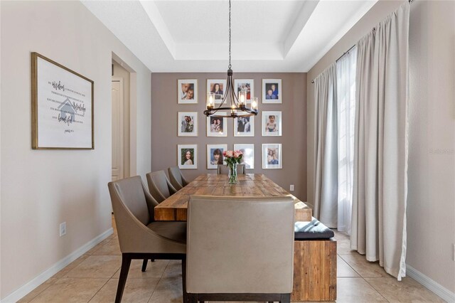 tiled dining space with a tray ceiling and an inviting chandelier