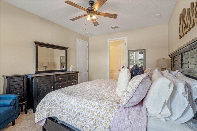 bedroom featuring ceiling fan, light carpet, and a textured ceiling