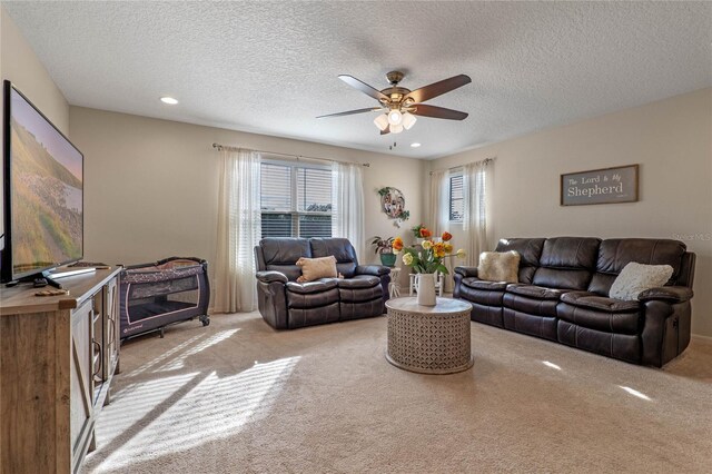 carpeted living room with ceiling fan and a textured ceiling