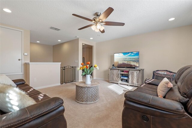 carpeted living room with ceiling fan and a textured ceiling