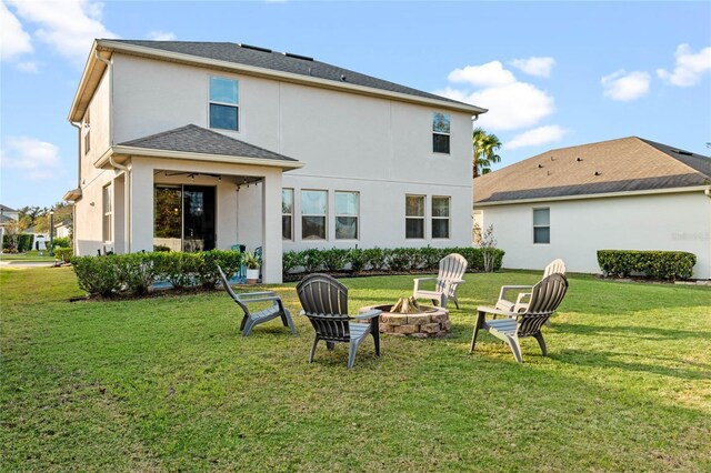 rear view of property with a fire pit and a lawn