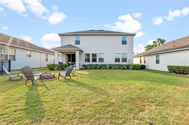 rear view of house with a fire pit and a lawn