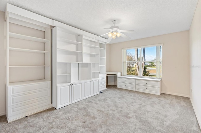 unfurnished bedroom featuring a textured ceiling, light colored carpet, and ceiling fan