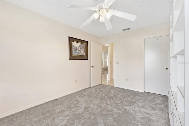 unfurnished bedroom with ceiling fan, light colored carpet, a textured ceiling, and a closet