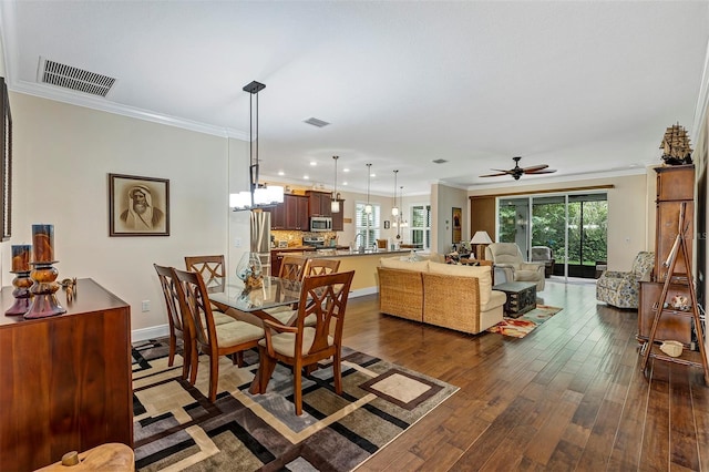 dining space with ceiling fan, ornamental molding, and dark wood-type flooring