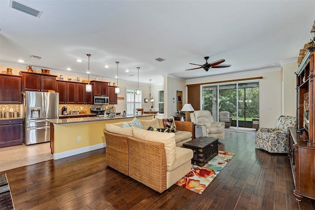 living room with ornamental molding, a wealth of natural light, dark wood-type flooring, and ceiling fan