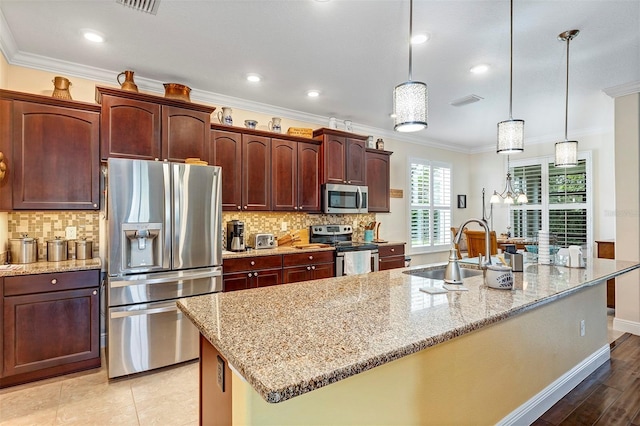 kitchen with sink, an island with sink, pendant lighting, and appliances with stainless steel finishes