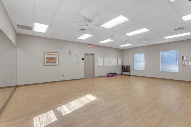 exercise room featuring ceiling fan, a drop ceiling, and light wood-type flooring