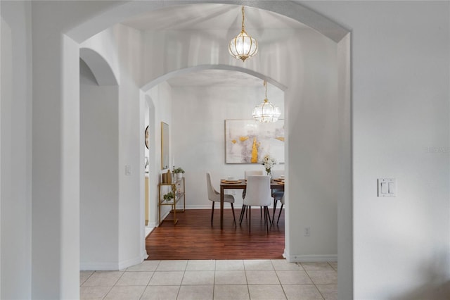 hallway featuring light tile patterned floors and a chandelier