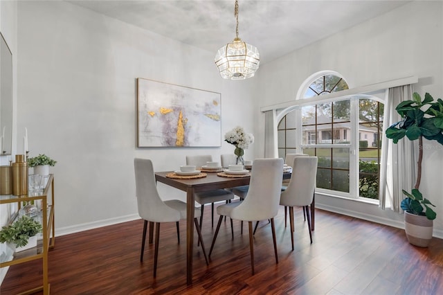 dining space featuring dark wood-type flooring, a notable chandelier, and a wealth of natural light