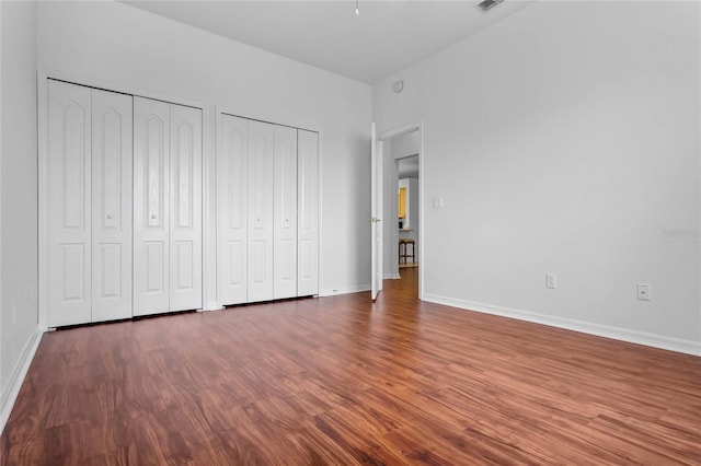 unfurnished bedroom with two closets and hardwood / wood-style flooring