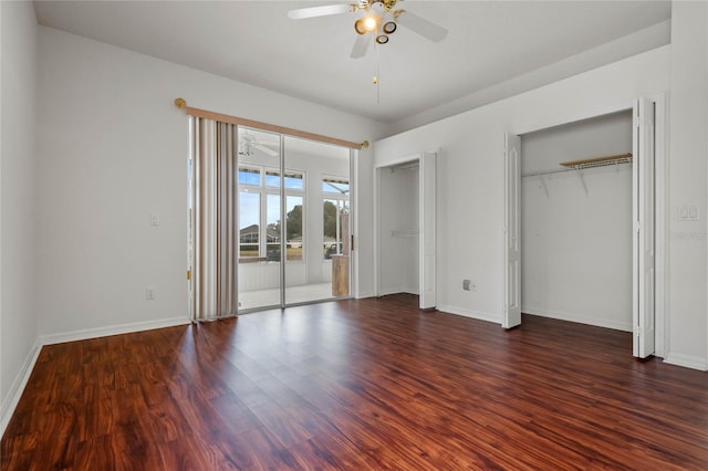 unfurnished bedroom featuring dark hardwood / wood-style flooring, multiple closets, and ceiling fan