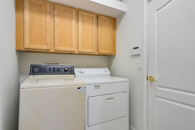 clothes washing area with washer and clothes dryer and cabinets