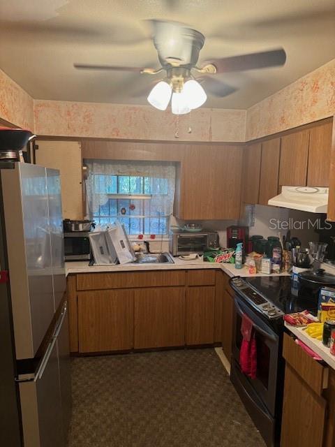 kitchen with black electric range, ventilation hood, stainless steel refrigerator, and ceiling fan