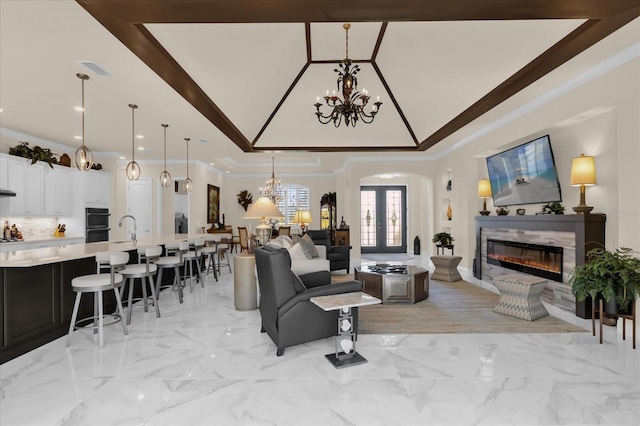 living room featuring a chandelier, french doors, crown molding, and sink