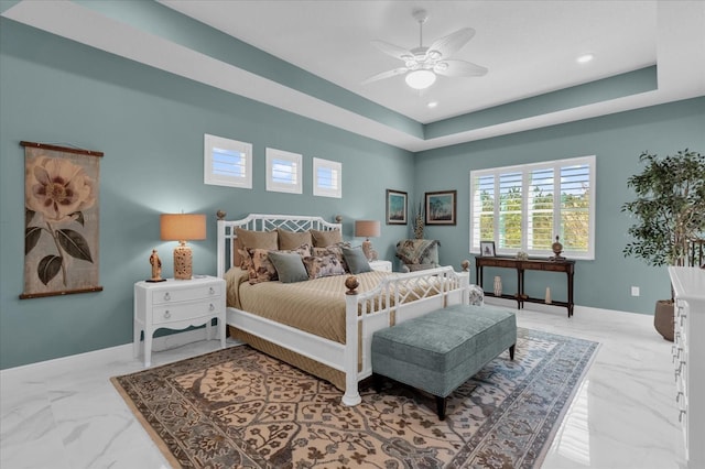 bedroom with ceiling fan and a raised ceiling