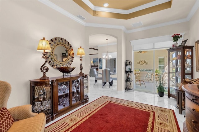 interior space with ceiling fan with notable chandelier, a raised ceiling, and ornamental molding