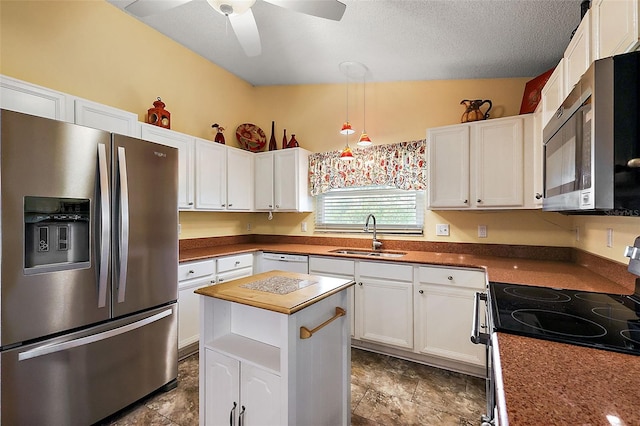 kitchen with appliances with stainless steel finishes, ceiling fan, sink, white cabinetry, and lofted ceiling