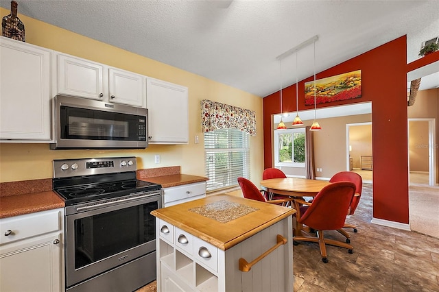 kitchen with pendant lighting, lofted ceiling, a textured ceiling, appliances with stainless steel finishes, and white cabinetry