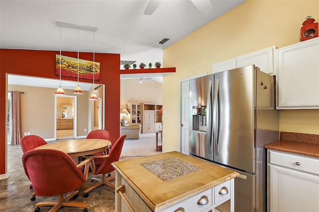 kitchen with a center island, ceiling fan, stainless steel fridge, decorative light fixtures, and white cabinetry