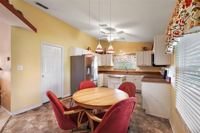 dining room with a textured ceiling, ceiling fan, lofted ceiling, and sink