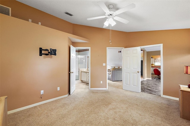 unfurnished bedroom featuring ensuite bath, light colored carpet, vaulted ceiling, and ceiling fan