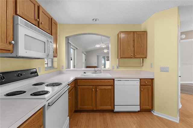 kitchen with a textured ceiling, white appliances, sink, light hardwood / wood-style flooring, and lofted ceiling