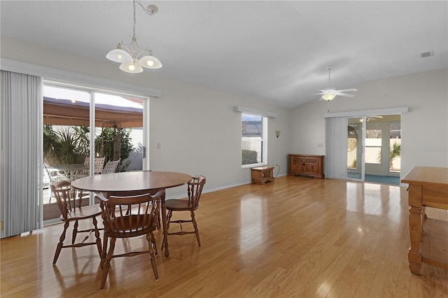 dining room with ceiling fan with notable chandelier, light hardwood / wood-style floors, a wealth of natural light, and lofted ceiling