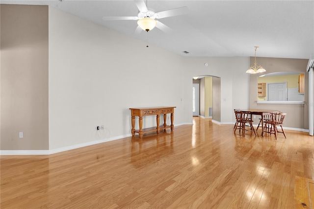 interior space with ceiling fan with notable chandelier, light wood-type flooring, and high vaulted ceiling