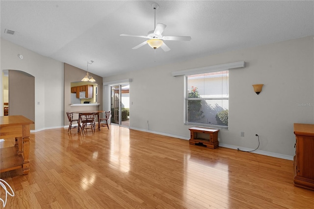 living room with a healthy amount of sunlight, light hardwood / wood-style floors, and vaulted ceiling