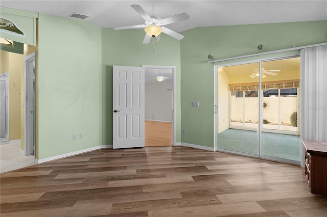 unfurnished bedroom featuring a textured ceiling, access to outside, ceiling fan, hardwood / wood-style floors, and lofted ceiling