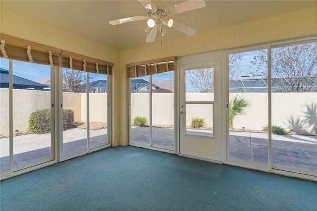 unfurnished sunroom featuring ceiling fan and a healthy amount of sunlight