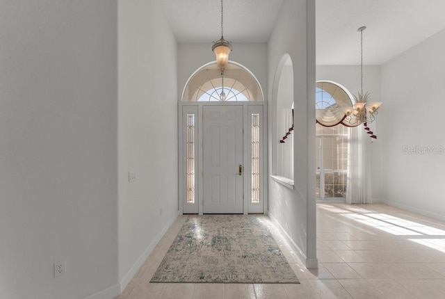 tiled entrance foyer with a chandelier