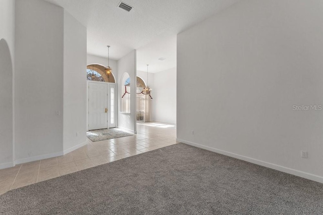 interior space with a textured ceiling, light carpet, and a chandelier