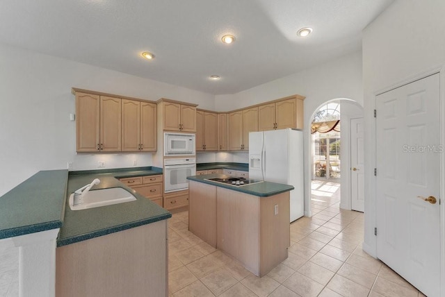 kitchen with light brown cabinets, white appliances, a kitchen island, and sink