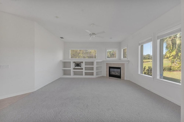 unfurnished living room with a tile fireplace, carpet floors, and ceiling fan