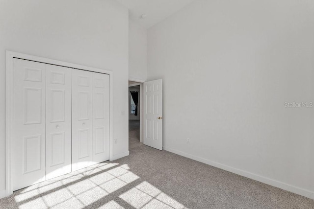 unfurnished bedroom featuring light carpet, a high ceiling, and a closet