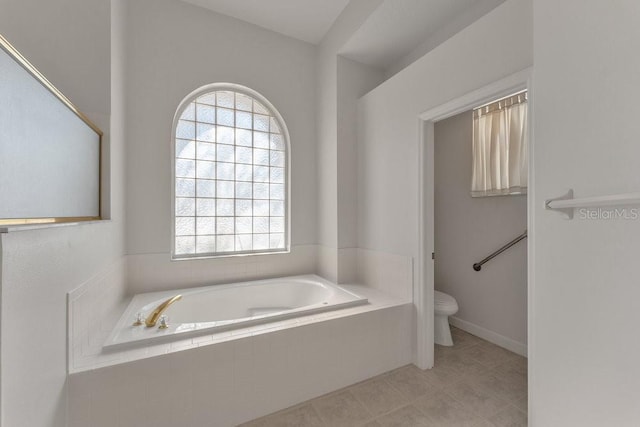 bathroom featuring tile patterned floors, toilet, and tiled tub