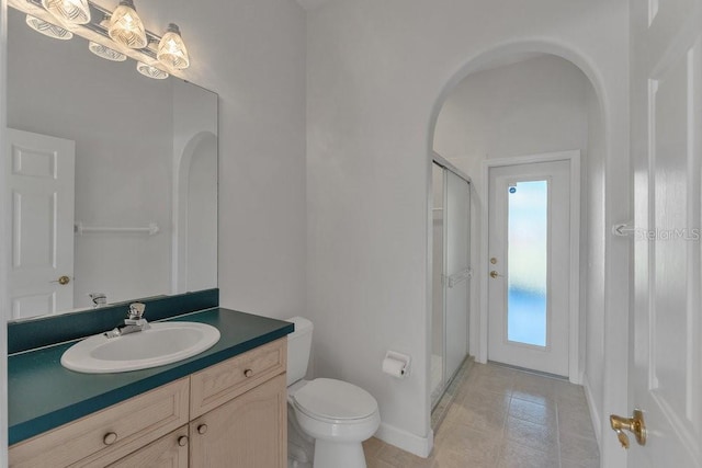 bathroom featuring tile patterned flooring, vanity, toilet, and a shower with shower door